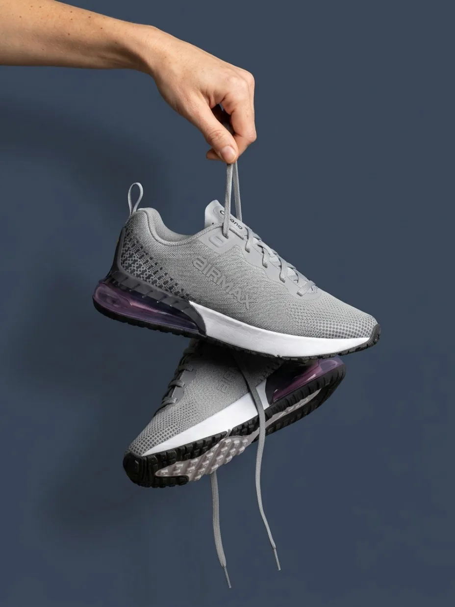 Shoe held by its laces above a reflection