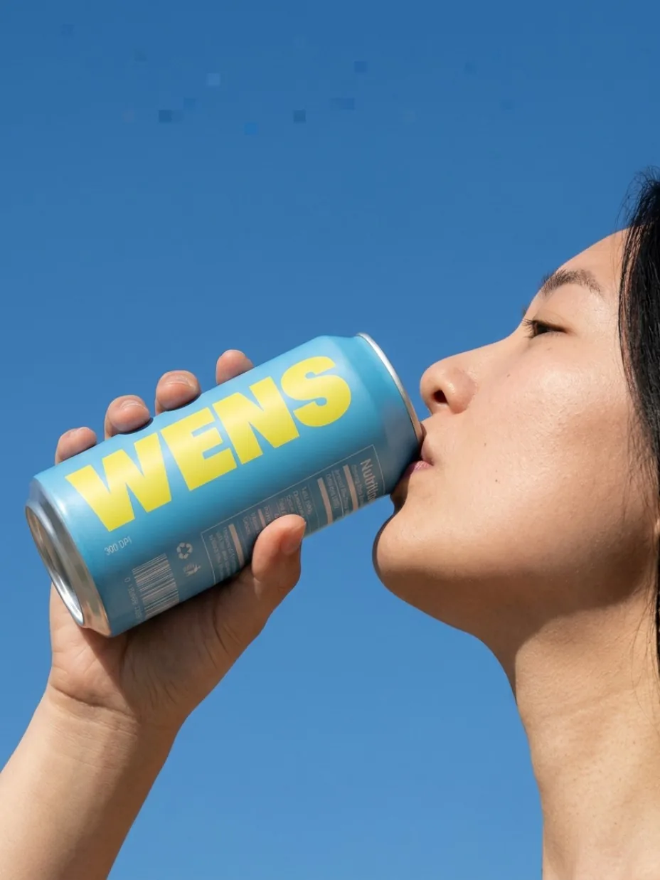 Profile of a person drinking from a can outdoors