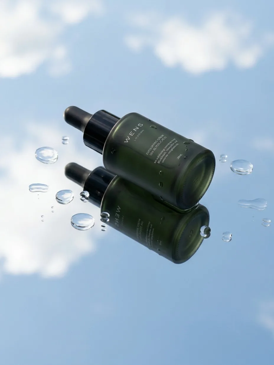 Perfume bottle on a reflective surface beneath the sky